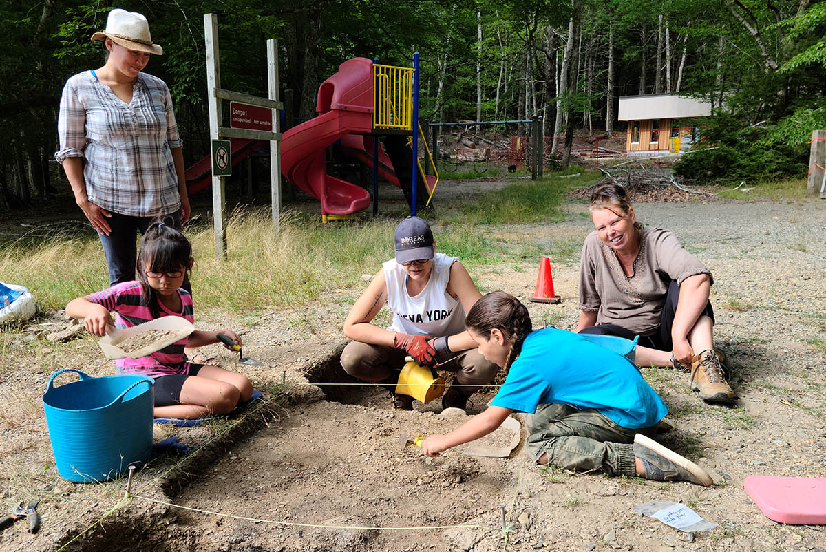 Children and adults digging at a real dig site.