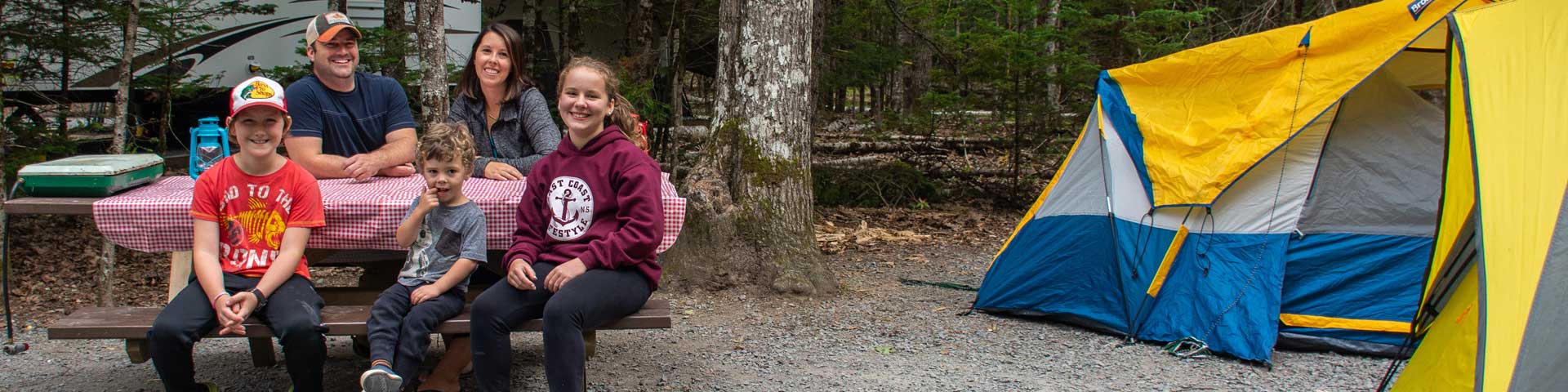 Une famille assise à une table de pique-nique à côté d'une tente.