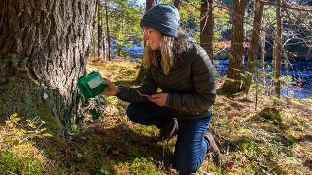 A woman holding a geocaching box. 