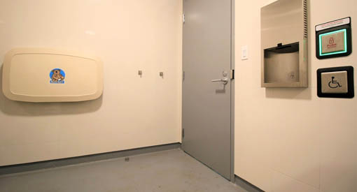 The family accessible washroom contains a baby change table, electrical outlet, waste bin, and push-button operated door.