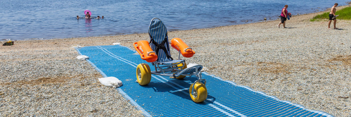 Un fauteuil roulant de plage flottant posé sur un tapis d’accès.