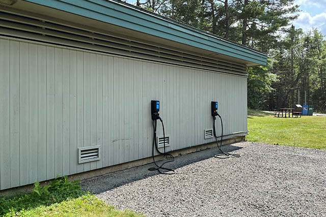 The EV charging stations are located on the side of the building next to a gravel parking lot.