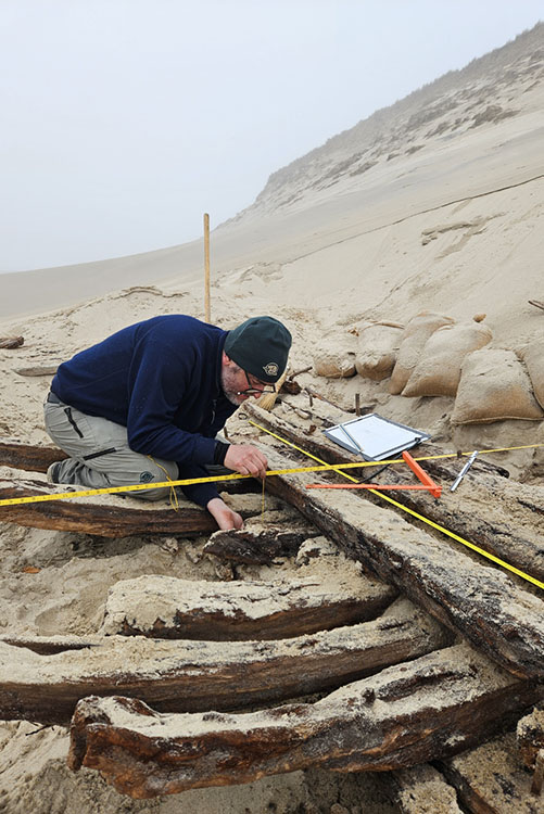 A person working next to the wreck section with a measuring tape.