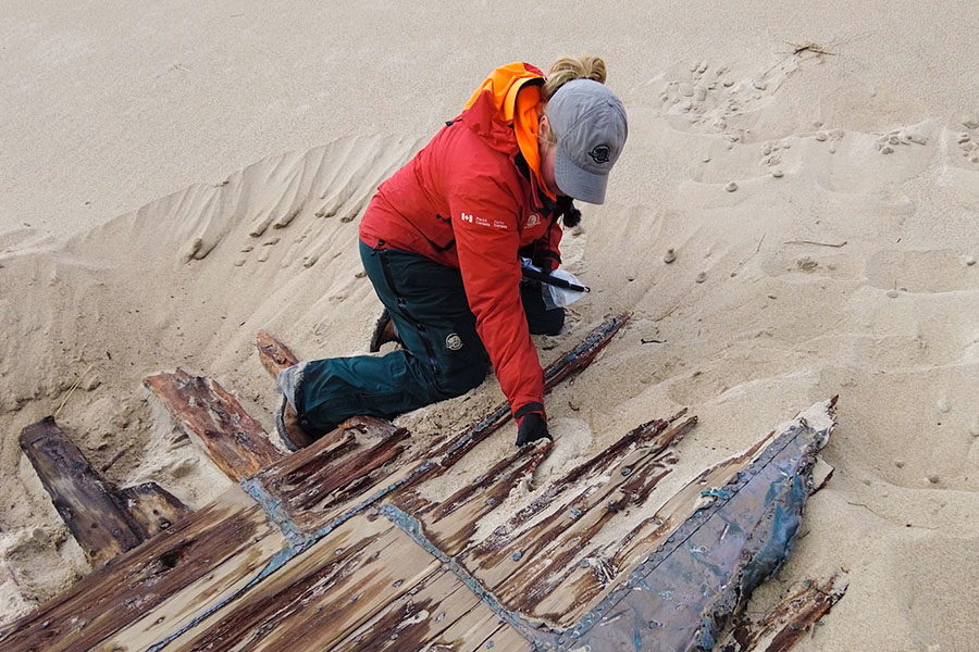 A person kneels beside a wreck section choosing a small piece to remove.