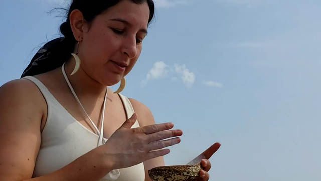 Une femme tient un coquillage avec de la sauge pour réaliser une purification.