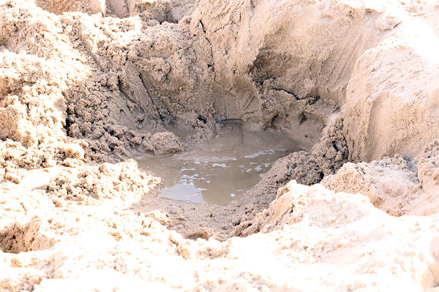 A small hole dug in the sand with water.