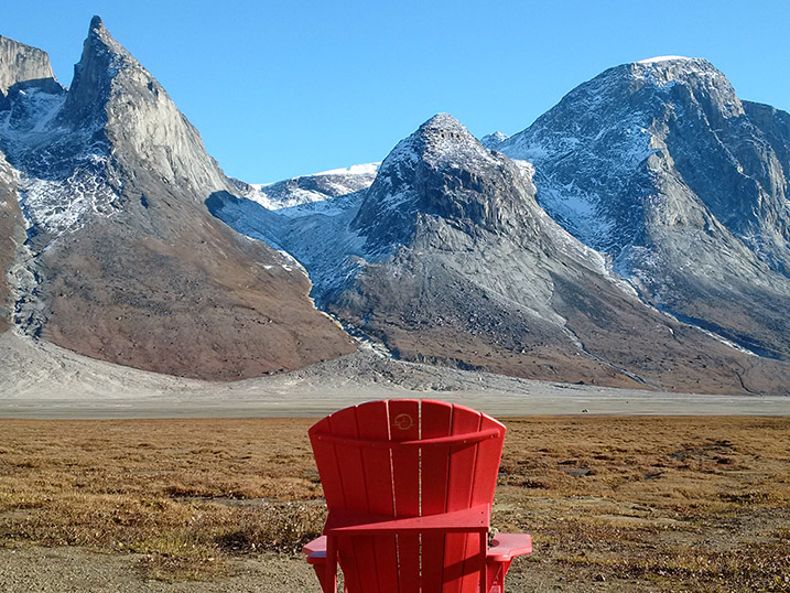 A Parks Canada red chair overlooking Ulu Peak and other mountain scenery.