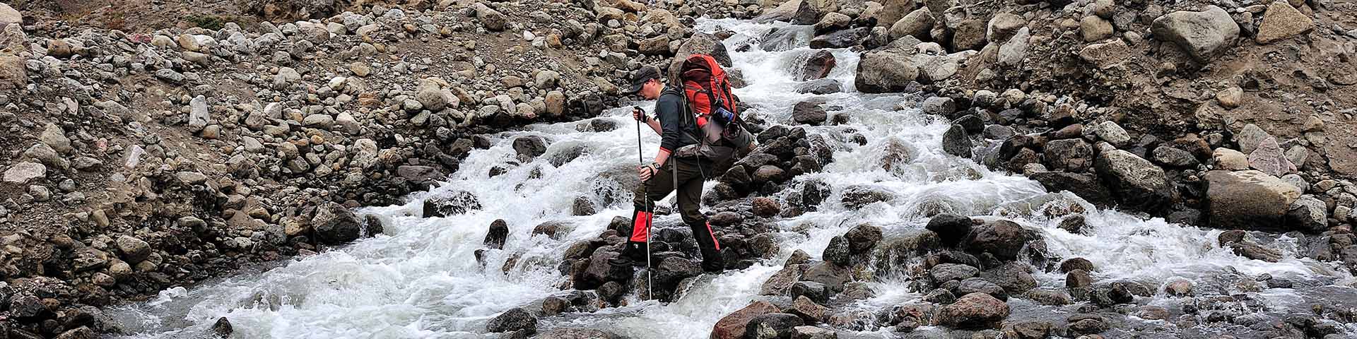 Un homme traversant une rivière dans le parc national Auyuittuq. 