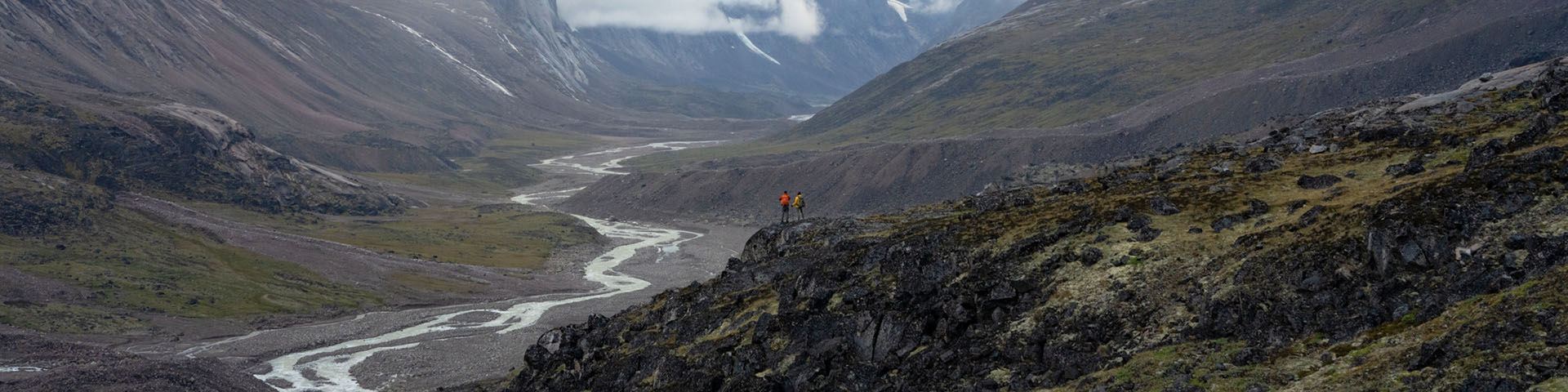 Two hikers overlooking a river in the Akshayuk Pass. 