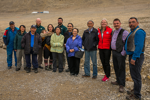 A group of people posing for a picture surrounded by tundra scenery.