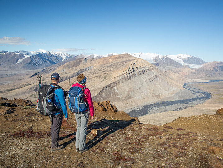 Two hikers overlooking a river valley and mountain scenery