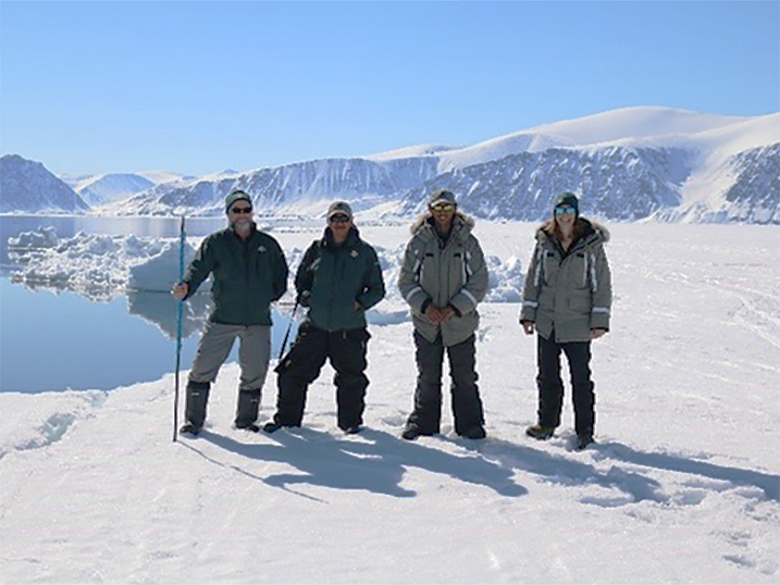 Four Parks Canada staff standing in a snowy landscape with mountain scenery