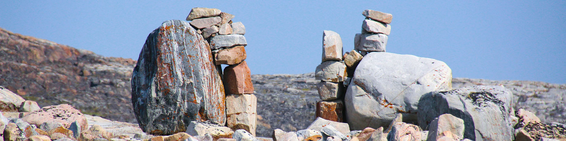 Two archaeological rock structures on a rocky landscape. 