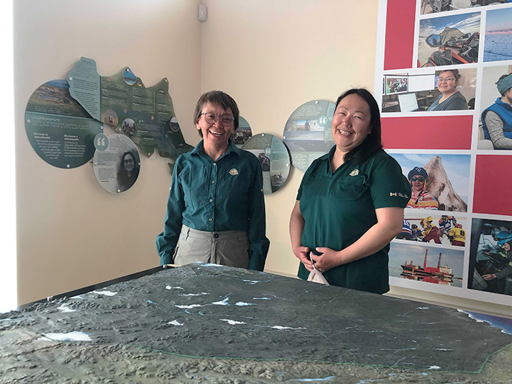 Two Parks Canada staff standing in front of a park exhibit