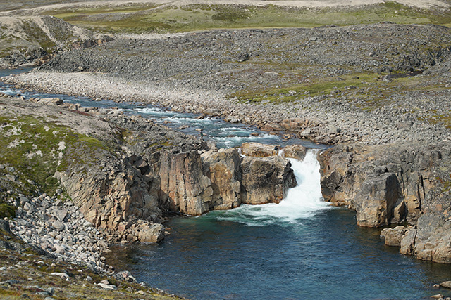 A waterfall flowing through a rocky landscape.