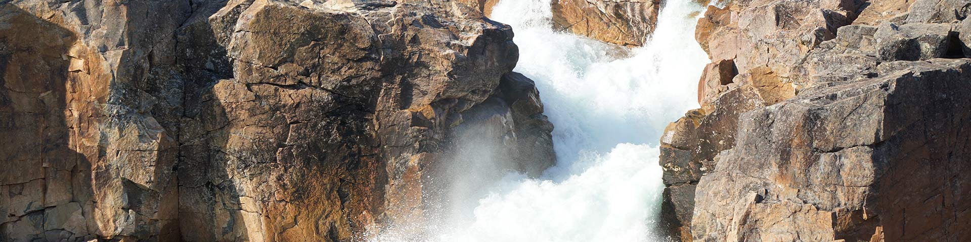 Waterfall cascading over orange-colored rocky terrain.