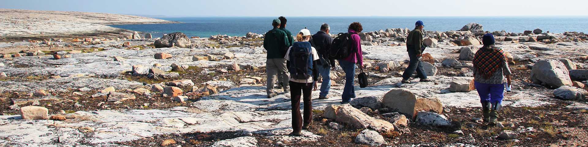 A group of people walking through a rocky tundra landscape. 