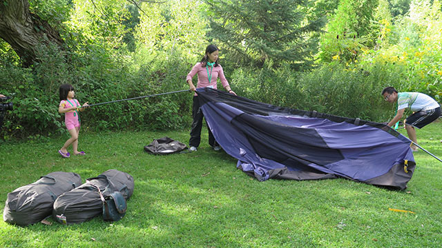 A family works to set up a tent. 