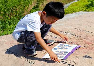 A young child works on an activity book on the shoreline