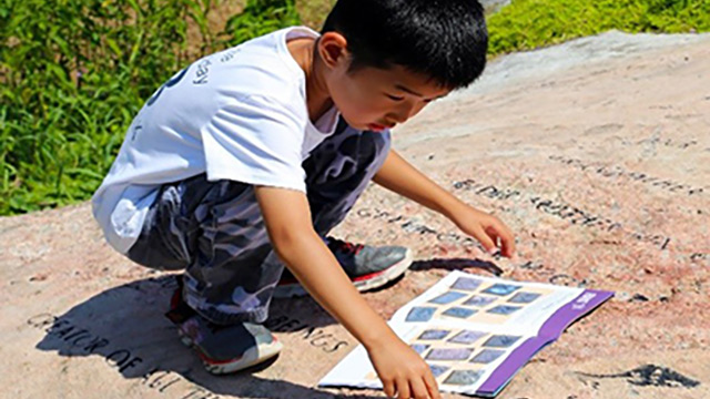 A young child works on an activity book on the shoreline
