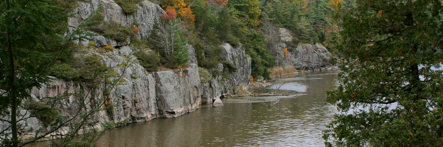 The natural shoreline with stone cliffs and trees