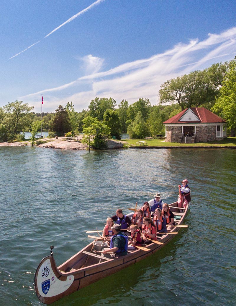 Ten people in a montreal canoe, on the water and close to shore