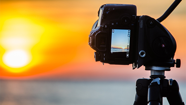 Appareil photo sur trépied prenant une photo du coucher de soleil