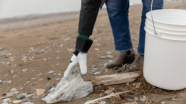 Person knelt on the beach picking up litter