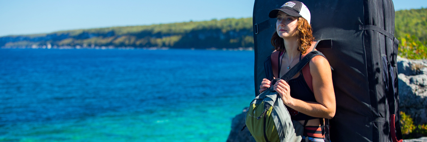 A woman with climbing safety gear hikes along the shoreline.