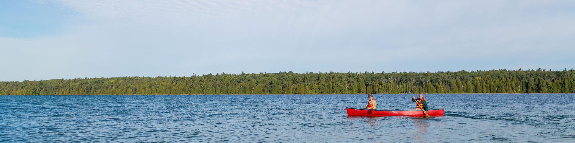 Une paire de paddle un canot rouge à travers un lac.