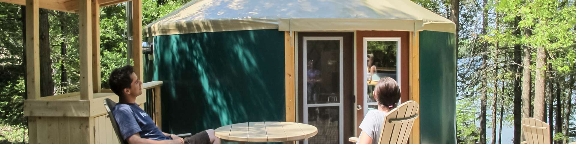 Two people sit in front of a yurt.