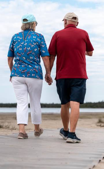 Deux personnes se promenant côte à côte sur une plage de sable.