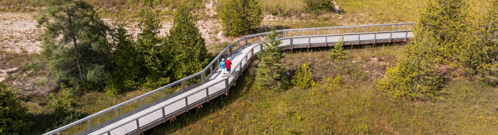 Des gens marchent le long d’une promenade de bois dans un paysage de terres humides côtières