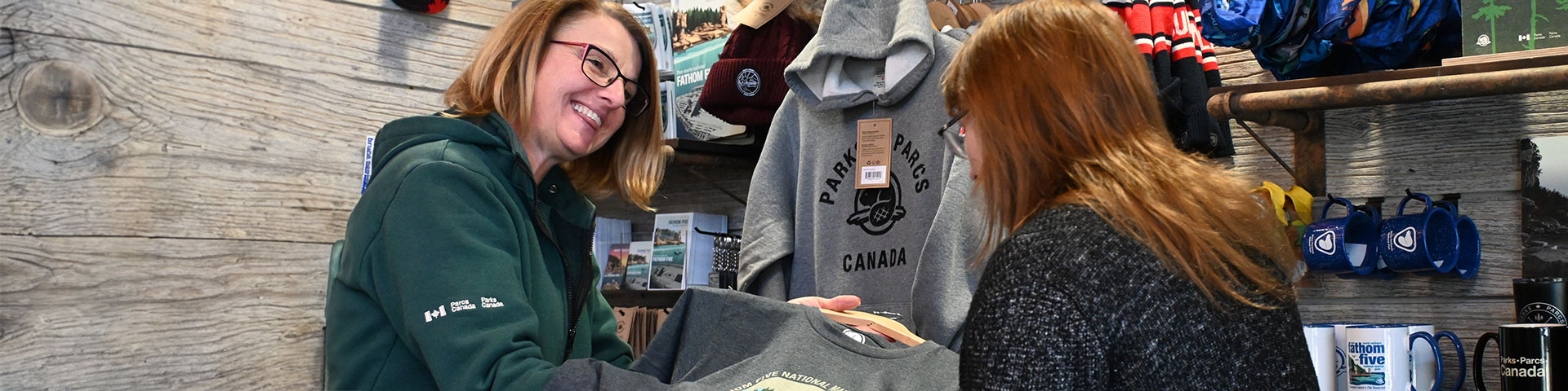 A staff member sowing a visitors a piece of clothing. 