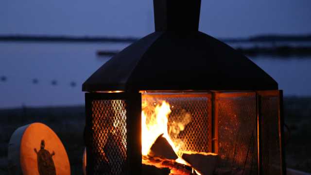 A drum sits beside a metal firebox with a fire burning inside.