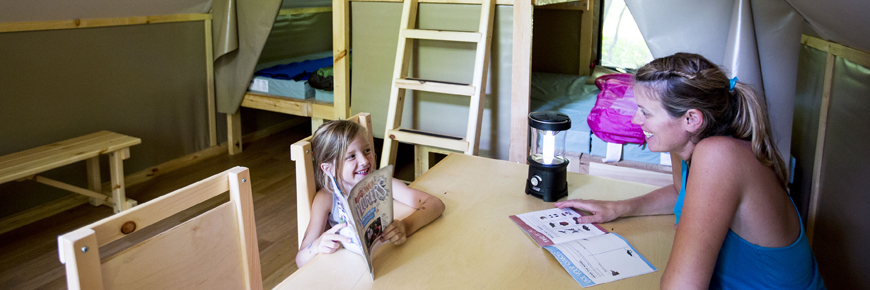 A mother and daughter sit at a table in an oTENTik. 