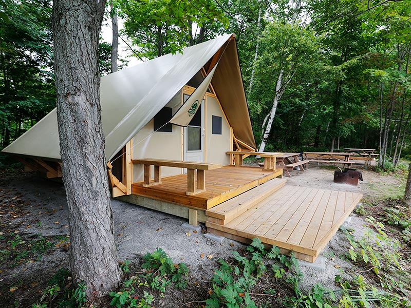 A canvas structure with wood deck in the forest.