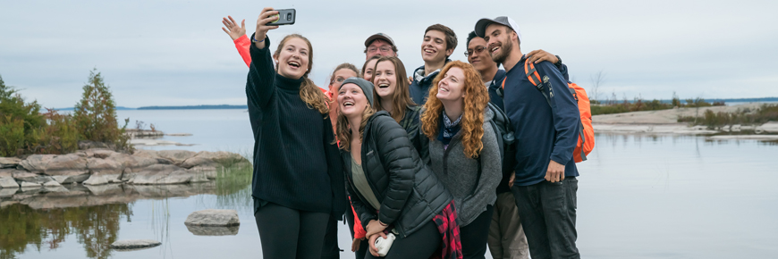 A group of hikers take a photo in front of the shoreline