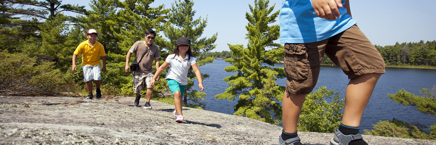 A family hikes along the rocky shoreline of Georgian Bay.