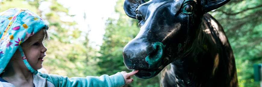 Un jeune visiteur interagissant avec une statue de caribou.