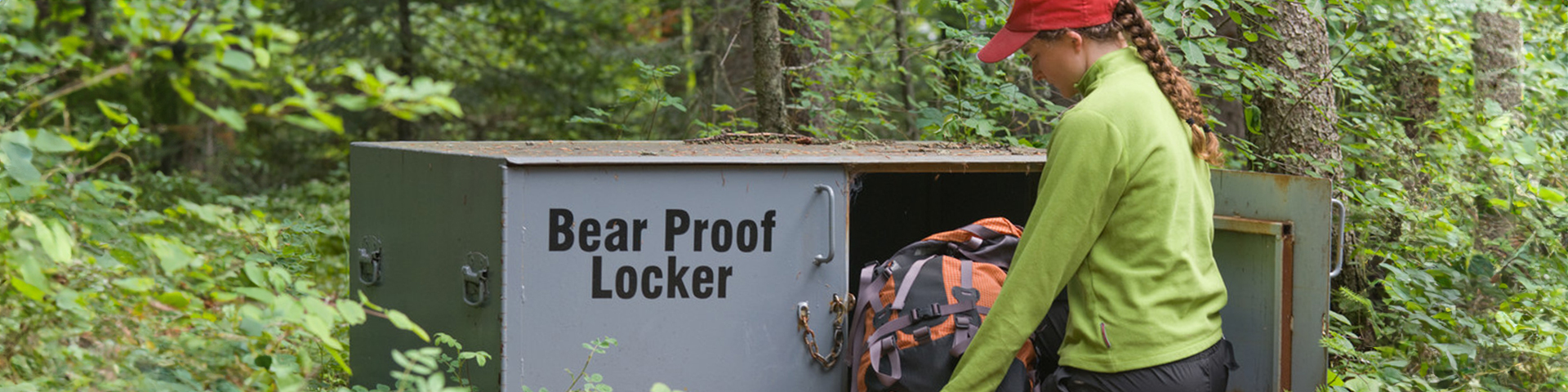 A visitor placing a backpack in a bear proof locker.