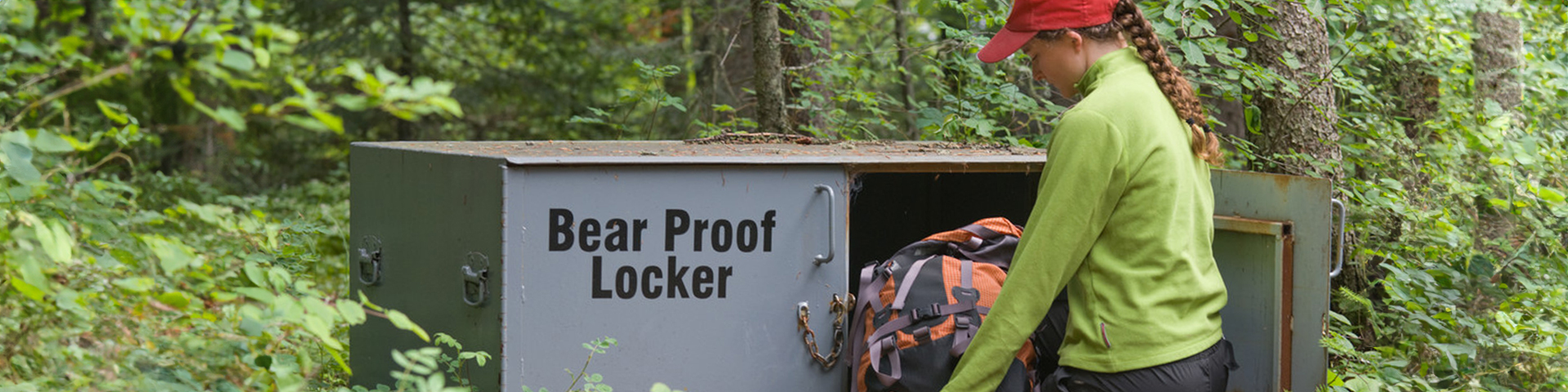 Un visiteur plaçant un sac à dos dans une armoire anti-ours.
