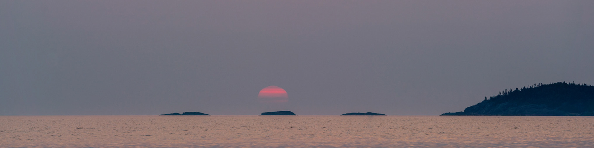 The sun setting over 3 islands.