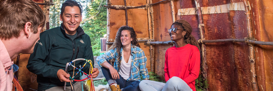 A group of people sitting inside a wiigwam