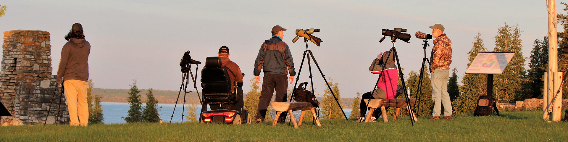 In the early morning light, birders look for spring migrants with their spotting scopes from the fort ruins.