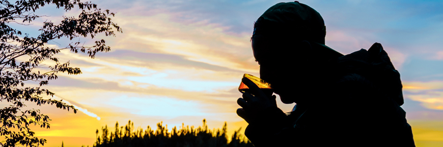 A person drinking hot chocolate at sunset.