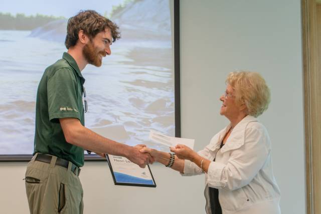 Pauline Browes presents a certificate to fellowship recipient Henri Lavallée during a ceremony..