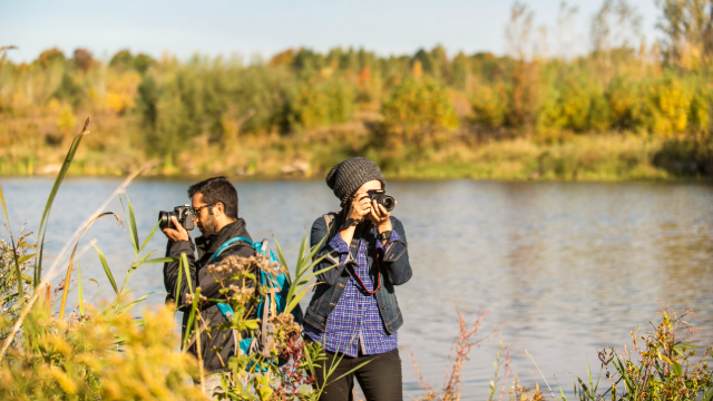 Two people photographing nature near a body of water at Rouge National Urban Park.