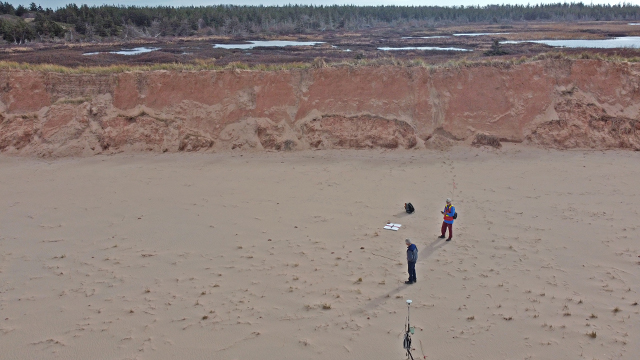 an aerial view of the beach in Greenwich of Dr. Ollerhead and Dr. Davidson-Arnot conducting research on the beach. They appear far in the distance and have a post in the sand. 