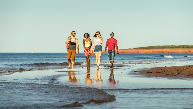 Quatre personnes se promenant sur la plage.